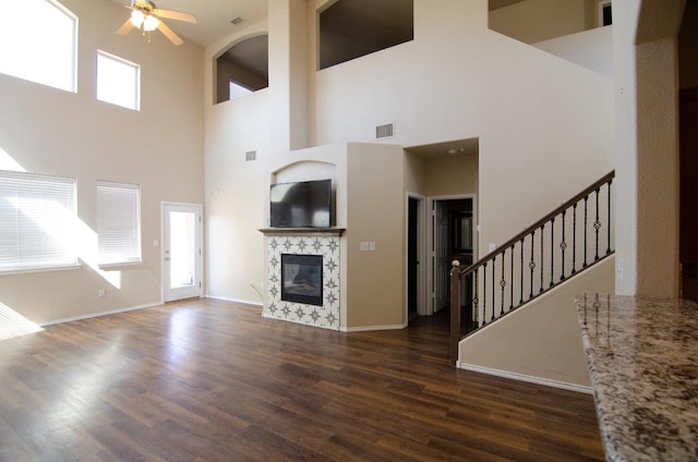 unfurnished living room featuring a premium fireplace, dark hardwood / wood-style floors, and ceiling fan