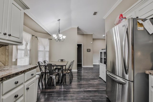 kitchen with lofted ceiling, white cabinetry, hanging light fixtures, freestanding refrigerator, and crown molding