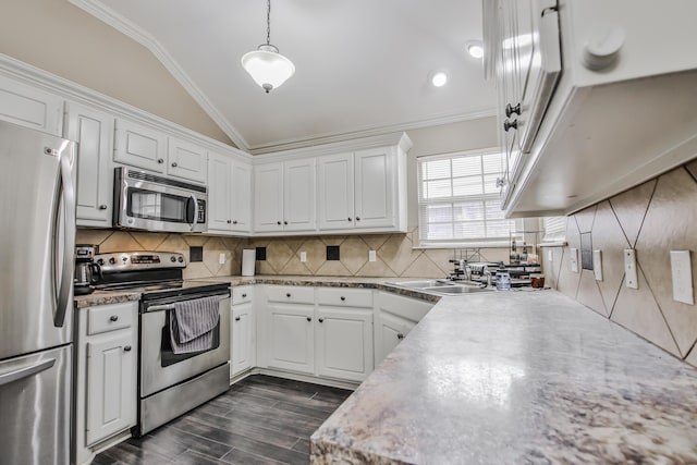 kitchen featuring white cabinets, ornamental molding, appliances with stainless steel finishes, pendant lighting, and a sink