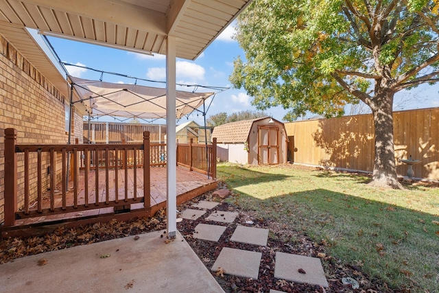 view of yard with a wooden deck, a storage shed, and a patio