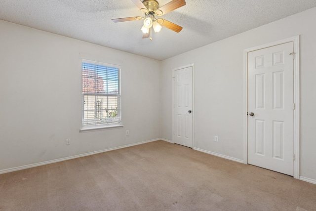 carpeted spare room featuring a textured ceiling and ceiling fan