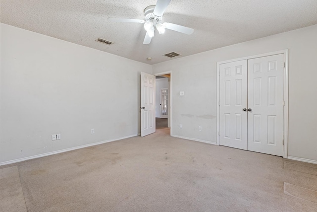 unfurnished bedroom with ceiling fan, light colored carpet, a closet, and a textured ceiling