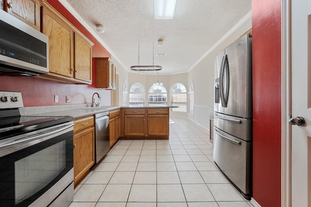 kitchen with light tile patterned floors, hanging light fixtures, stainless steel appliances, ornamental molding, and kitchen peninsula