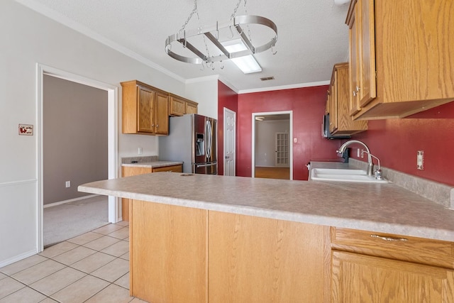 kitchen with ornamental molding, sink, stainless steel fridge, and kitchen peninsula