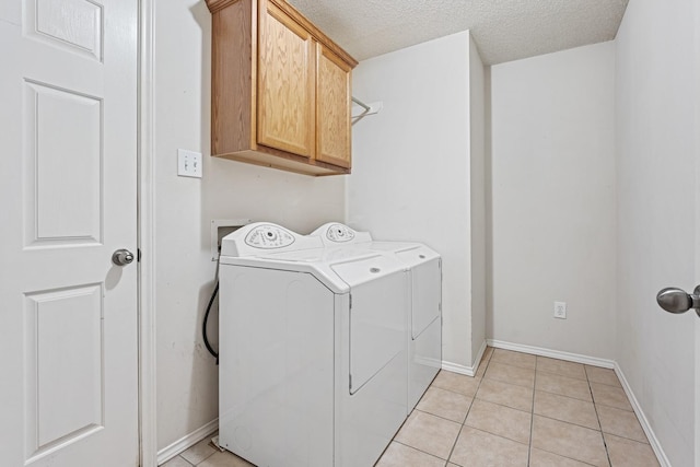 washroom featuring cabinets, washer and dryer, light tile patterned floors, and a textured ceiling