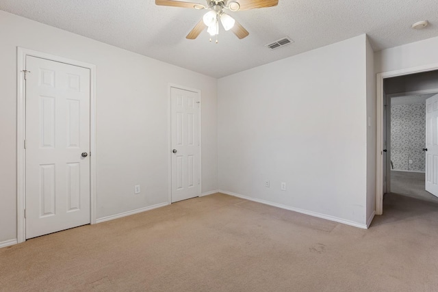 unfurnished bedroom with ceiling fan, light carpet, and a textured ceiling