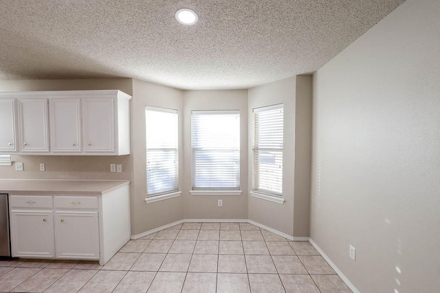 kitchen featuring white cabinetry, dishwashing machine, a textured ceiling, and light tile patterned flooring