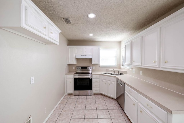 kitchen featuring light tile patterned flooring, sink, a textured ceiling, appliances with stainless steel finishes, and white cabinets