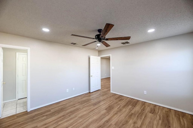 spare room featuring ceiling fan, light hardwood / wood-style floors, and a textured ceiling