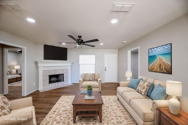 living room featuring ceiling fan, hardwood / wood-style floors, and a fireplace