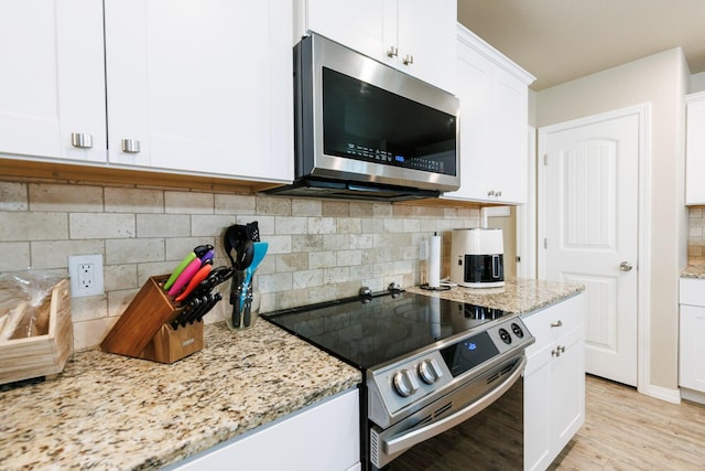 8812 16th St, Lubbock, TX 79416 - kitchen featuring white cabinets, light stone countertops, appliances with stainless steel finishes, light wood-type flooring, and backsplash