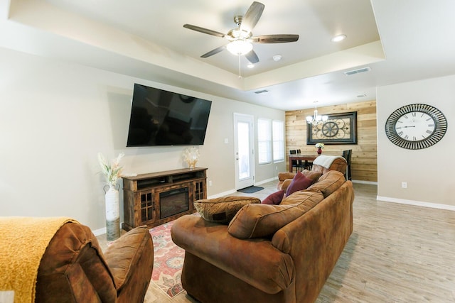 8812 16th St, Lubbock, TX 79416 - living area featuring wooden walls, a raised ceiling, ceiling fan with notable chandelier, baseboards, and light wood-type flooring