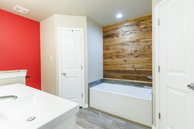 8812 16th St, Lubbock, TX 79416 - bathroom with visible vents, wood finished floors, recessed lighting, a bathing tub, and a sink