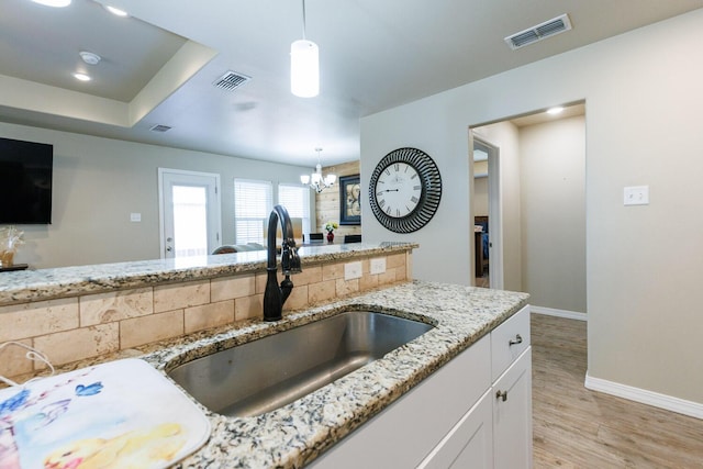8812 16th St, Lubbock, TX 79416 - kitchen featuring baseboards, light stone countertops, visible vents, and a sink