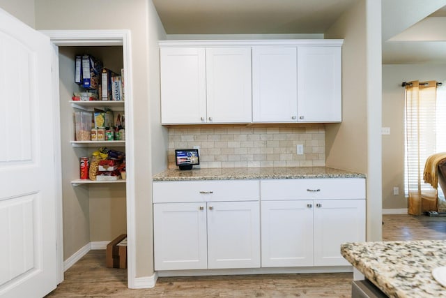 8812 16th St, Lubbock, TX 79416 - kitchen featuring light wood-style floors, baseboards, white cabinets, tasteful backsplash, and light stone counters