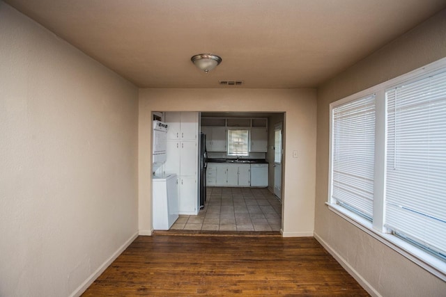 corridor with stacked washer and dryer, dark hardwood / wood-style flooring, and sink