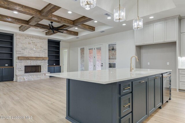 7726 46th St, Lubbock, TX 79407 - kitchen featuring a stone fireplace, ceiling fan, light wood-style flooring, an island with sink, and recessed lighting