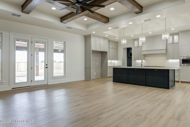 7726 46th St, Lubbock, TX 79407 - kitchen with coffered ceiling, decorative backsplash, stainless steel microwave, custom exhaust hood, and light wood-style flooring