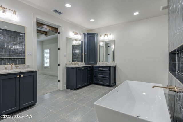 7726 46th St, Lubbock, TX 79407 - bathroom featuring two vanities, tile patterned floors, a freestanding bath, and recessed lighting