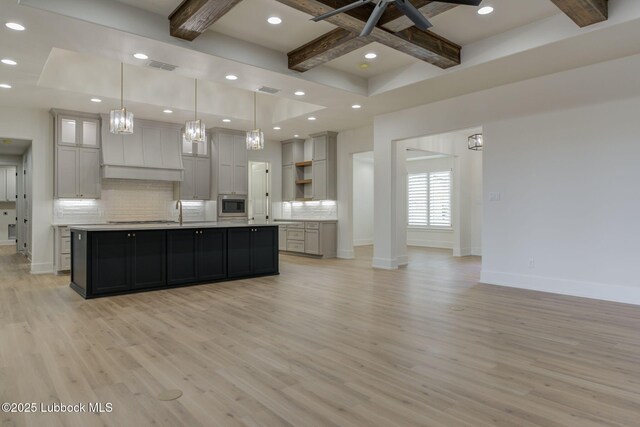 7726 46th St, Lubbock, TX 79407 - kitchen with open shelves, stainless steel microwave, tasteful backsplash, light countertops, and premium range hood