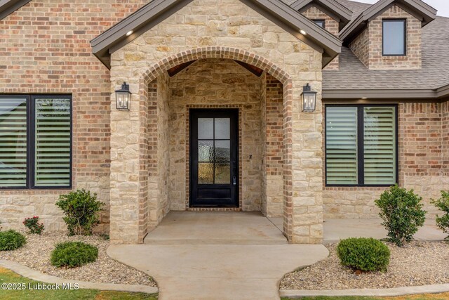 7726 46th St, Lubbock, TX 79407 - property entrance featuring stone siding, roof with shingles, and brick siding