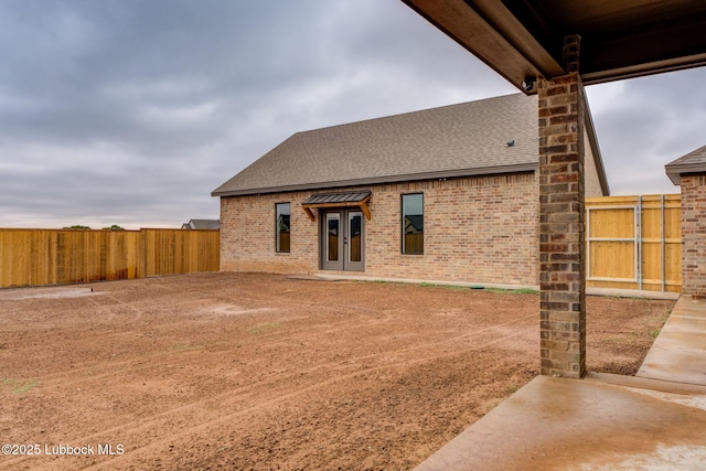 7726 46th St, Lubbock, TX 79407 - rear view of property with a shingled roof, brick siding, a fenced backyard, and french doors