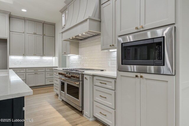 7726 46th St, Lubbock, TX 79407 - kitchen with appliances with stainless steel finishes, custom range hood, recessed lighting, light wood-style floors, and light stone countertops