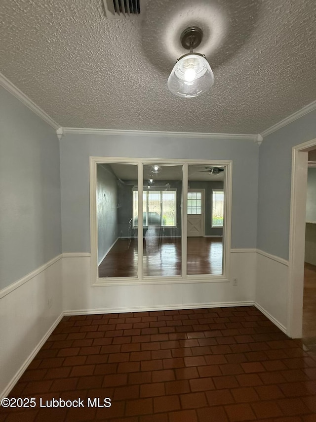 3506 97th St, Lubbock, TX 79423 - unfurnished room with a wainscoted wall, crown molding, a textured ceiling, and brick patterned floors