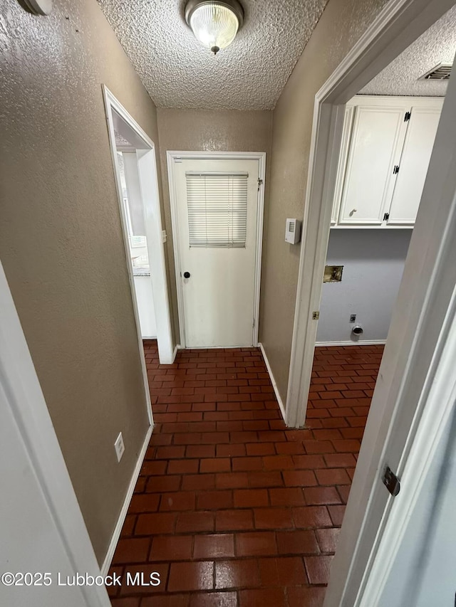 3506 97th St, Lubbock, TX 79423 - hall featuring a textured ceiling, baseboards, and brick flooring
