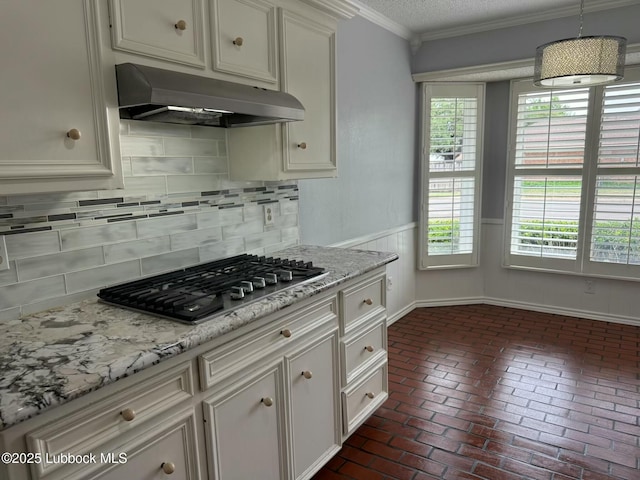 3506 97th St, Lubbock, TX 79423 - kitchen featuring under cabinet range hood, stainless steel gas stovetop, brick flooring, ornamental molding, and tasteful backsplash
