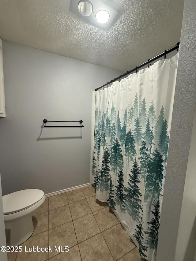 3506 97th St, Lubbock, TX 79423 - bathroom featuring toilet, tile patterned flooring, a textured ceiling, baseboards, and a shower with shower curtain