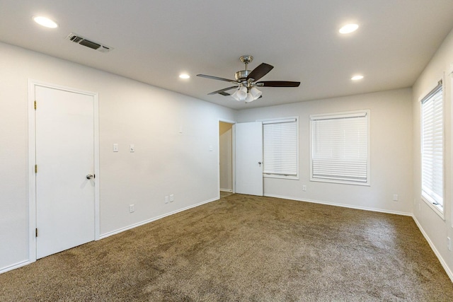 unfurnished room featuring ceiling fan and dark colored carpet