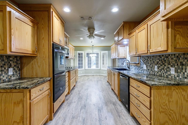 kitchen with sink, dishwashing machine, ceiling fan, and dark stone counters