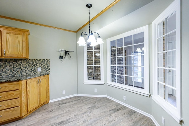 unfurnished dining area featuring crown molding, a notable chandelier, and light hardwood / wood-style flooring