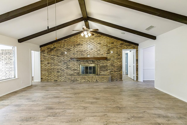 unfurnished living room featuring brick wall, wood-type flooring, a brick fireplace, and vaulted ceiling with beams