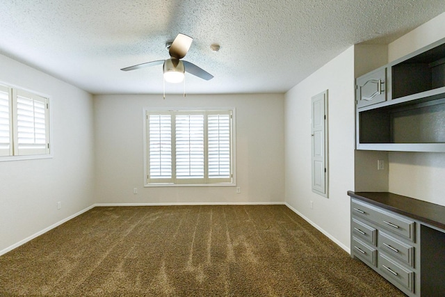 unfurnished room with a textured ceiling, ceiling fan, and dark colored carpet