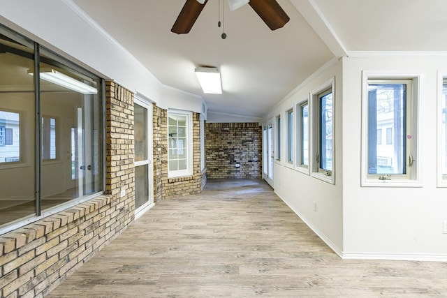 hall featuring light wood-type flooring, ornamental molding, and brick wall