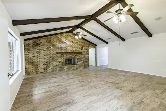 unfurnished living room featuring brick wall, a brick fireplace, vaulted ceiling with beams, and hardwood / wood-style floors