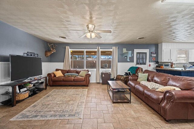 living room with a textured ceiling and ceiling fan