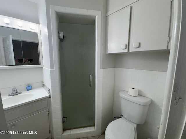 2721 52nd St, Lubbock, TX 79413 - bathroom with toilet, tile walls, vanity, a stall shower, and wainscoting