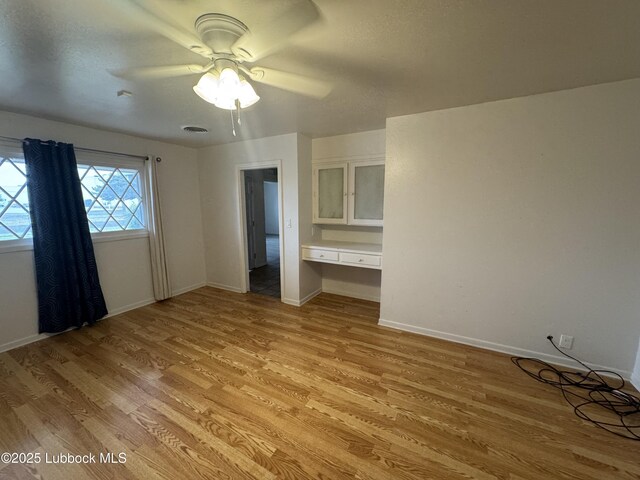 2721 52nd St, Lubbock, TX 79413 - unfurnished bedroom with baseboards, light wood finished floors, ceiling fan, and built in desk