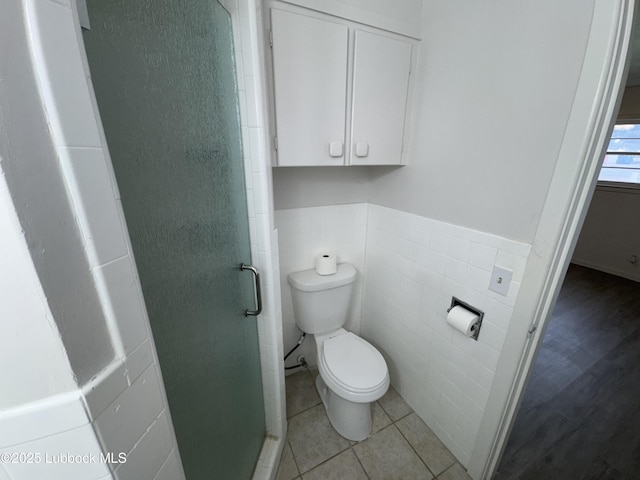 2721 52nd St, Lubbock, TX 79413 - bathroom featuring a stall shower, tile walls, toilet, wainscoting, and tile patterned floors