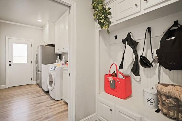 clothes washing area featuring separate washer and dryer, light hardwood / wood-style flooring, and cabinets