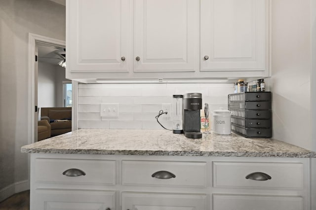 kitchen with light stone countertops, white cabinets, and decorative backsplash