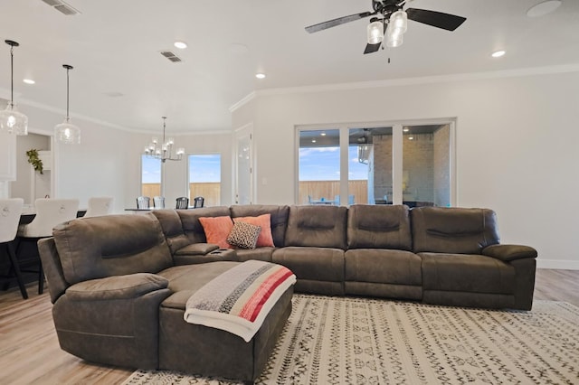 living room with ceiling fan with notable chandelier, ornamental molding, light hardwood / wood-style floors, and a healthy amount of sunlight