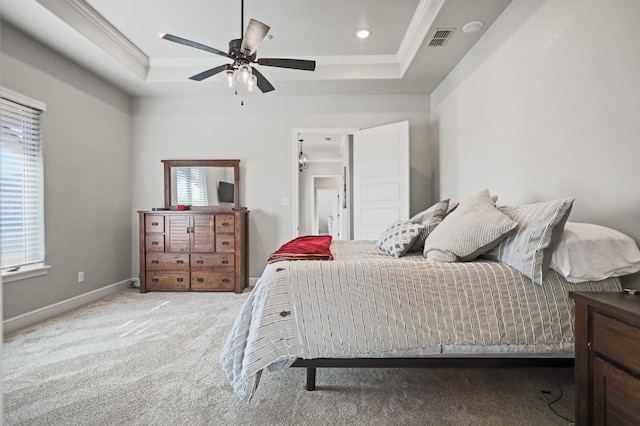 carpeted bedroom with a raised ceiling, crown molding, and multiple windows