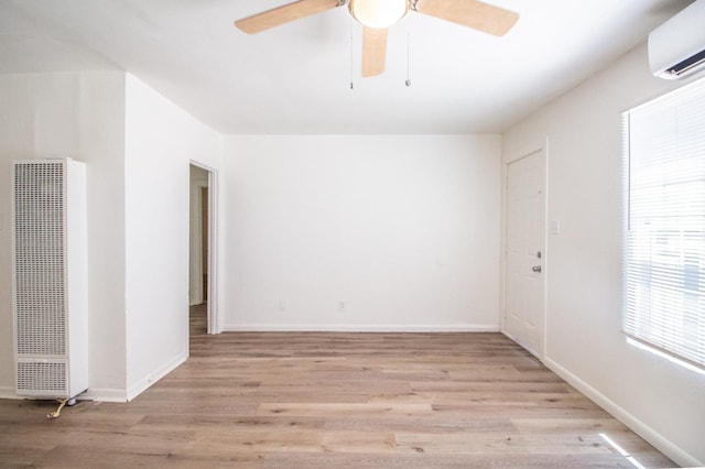 empty room featuring ceiling fan, a wall unit AC, and light wood-type flooring