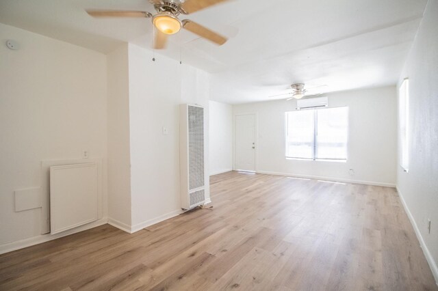 unfurnished room featuring ceiling fan, a wall unit AC, and light wood-type flooring