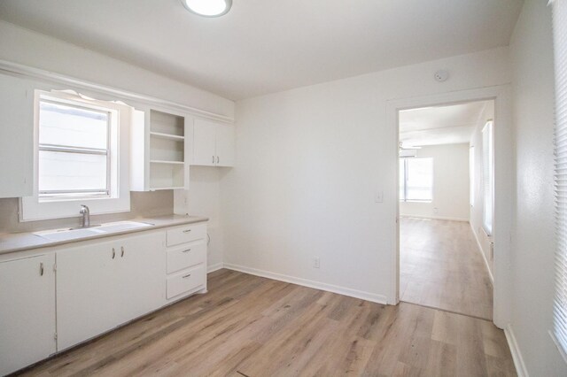 kitchen with white cabinetry, sink, and light hardwood / wood-style floors