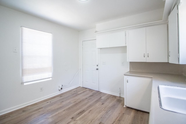 kitchen with sink, white cabinets, and light hardwood / wood-style flooring